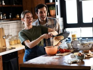 husband,and,wife,making,pancakes,at,home.,young,couple,having