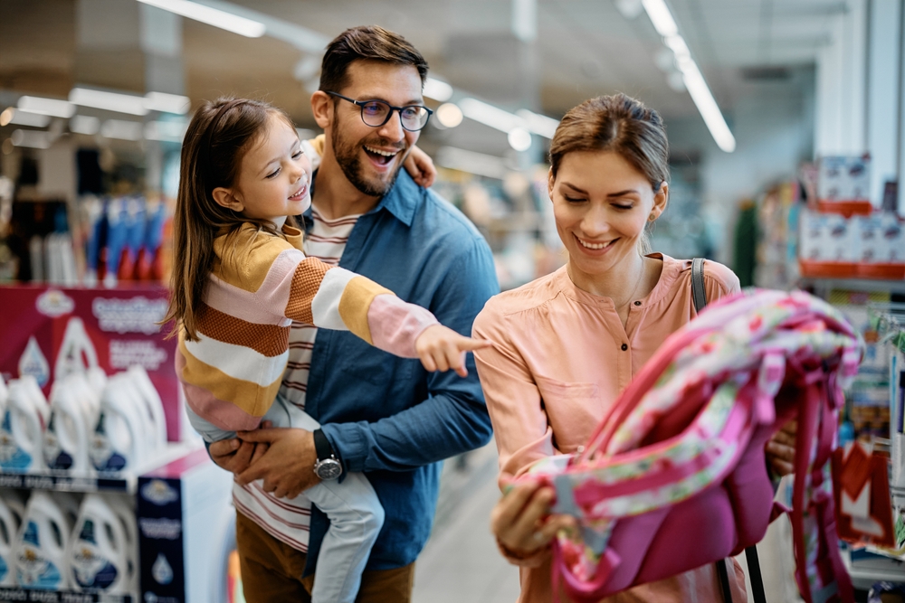 happy,little,girl,pointing,at,backpack,while,buying,school,supplies